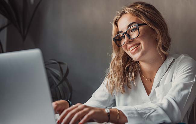 Woman smiling while managing Facebook ad campaigns on her laptop
