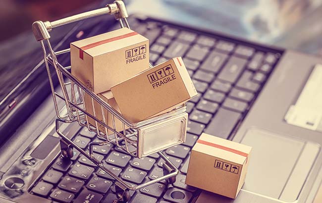Tiny shopping trolley with packages on a laptop keyboard symbolising eCommerce SEO