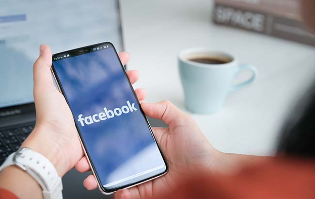 Person holding smartphone with Facebook app open — representing Facebook Ads in action